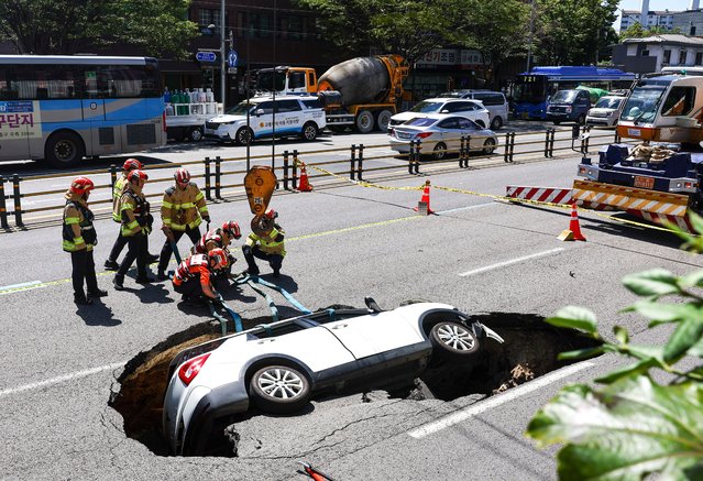 Firefighters prepare to remove a car from a sinkhole that emerged in the middle of a road in Seoul, South Korea, 29 August 2024. According to fire authorities, two people were injured after a car plunged into the sinkhole. (Photo by Yonhap/EPA/EFE)