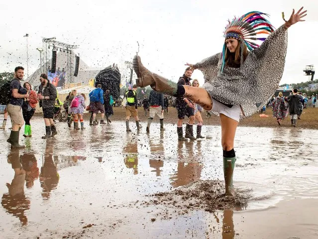 A woman kicks water in a puddle as she poses for photographers, on the first official day of the Glastonbury Festival of Music and Performing Arts on Worthy Farm in Somerset, south west England, on June 27, 2014. (Photo by Leon Neal/AFP Photo)