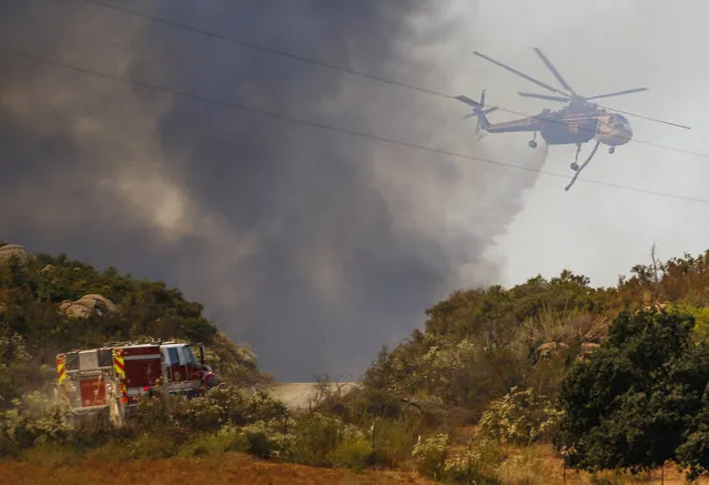 A helicopter drops water on a wildfire burning close to Highway 94 near Potrero, Calif., on Monday, June 20, 2016. (Photo by Hayne Palmour IV/San Diego Union-Tribune via AP Photo)