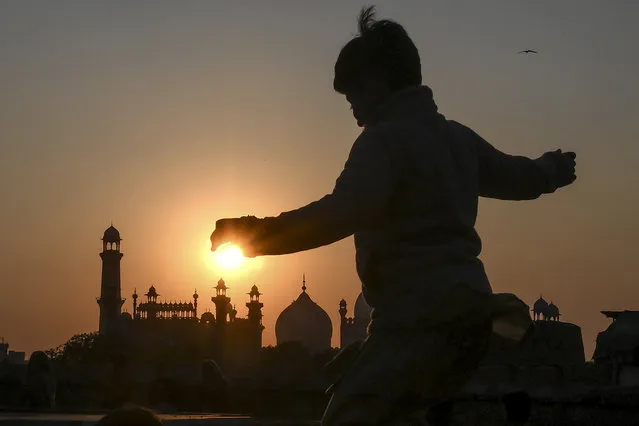 A boy plays near the historical Badshahi Mosque during sunset in Lahore, Punjab Province on January 9, 2020. (Photo by Arif Ali/AFP Photo)