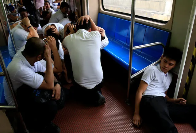 Mock victims acting as Light Rail Transit (LRT) commuters take cover inside the passenger coach as they participate in a metrowide simultaneous earthquake drill in metro Manila, Philippines June 22, 2016. (Photo by Romeo Ranoco/Reuters)