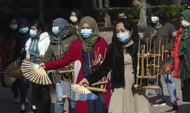 Indonesian migrant workers wear face masks as they play the traditional music instrument “angklung” in Hong Kong, Monday, January 27, 2020. Hong Kong announced it would bar entry to visitors from the mainland province at the center of the outbreak. Travel agencies were ordered to cancel group tours nationwide following a warning the virus's ability to spread was increasing. (Photo by Achmad Ibrahim/AP Photo)