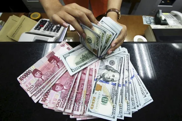 A teller at a money changer displays Indonesian Rupiah and US dollars in Jakarta, Indonesia August 12, 2015 in this photo taken by Antara Foto. Indonesia's central bank was spotted “heavily” intervening to defend the rupiah on Wednesday, traders said, as the currency fell to a level last seen during the Asian financial crisis 17 years ago. (Photo by Rivan Awal Lingga/Reuters/Antara Foto)