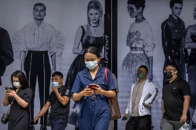 Commuters wearing face masks walk out from the entrance of a subway station in the central business district in Beijing, Friday, June 17, 2022. (Photo by Mark Schiefelbein/AP Photo)