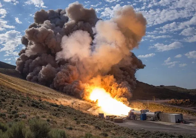 The second and final qualification motor (QM-2) test for the Space Launch System's booster is seen June 28, 2016, at Orbital ATK Propulsion Systems test facilities in Promontory, Utah. During the Space Launch System flight the boosters will provide more than 75 percent of the thrust needed to escape the gravitational pull of the Earth, the first step on NASA's Journey to Mars. Fire and gray smoke billowed from the booster, which lay on the ground during the two-minute test fire in the remote hills of Utah at 11:05 am (1605 GMT). (Photo by Bill Ingalls/AFP Photo/NASA)