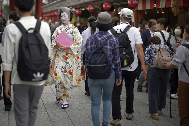 A Geisha woman in traditional Japanese “kimono” walks along a shopping street at the Asakusa district Friday, June 10, 2022, in Tokyo. (Photo by Eugene Hoshiko/AP Photo)
