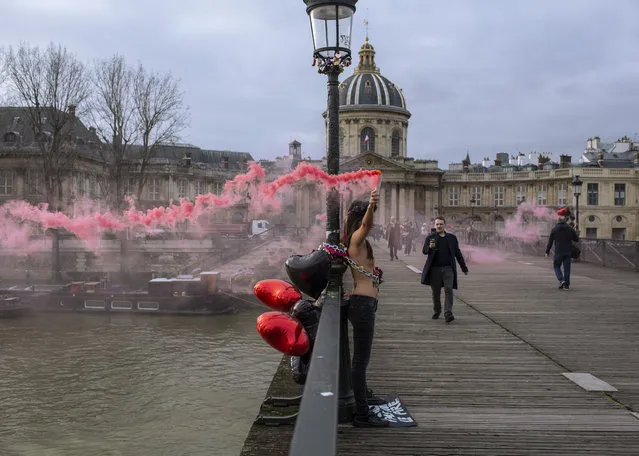 Femen activists hold pink flares during a protest on the Pont des Arts in Paris, Friday, February 14, 2020. Femen activists staged a protest against domestic violence to mark Valentine's day. (Photo by Rafael Yaghobzadeh/AP Photo)