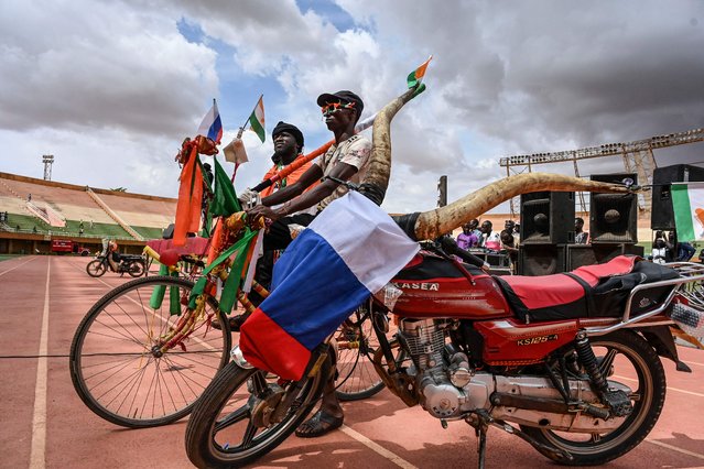 Supporters stand next to a motorbike adorned with zebu horns and a Russian flag at a concert in support to Niger's National Council for the Safeguard of the Homeland (CNSP) at the General Seyni Kountche Stadium in Niamey on August 13, 2023. (Photo by AFP Photo/Stringer)