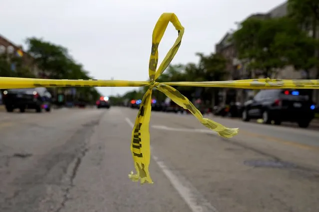 Police tape hangs at corner of Central Avenue and Green Bay Rd., in Highland Park, a Chicago suburb, Monday, July 4, 2022, after a mass shooting at Highland Park Fourth of July parade. (Photo by Nam Y. Huh/AP Photo)