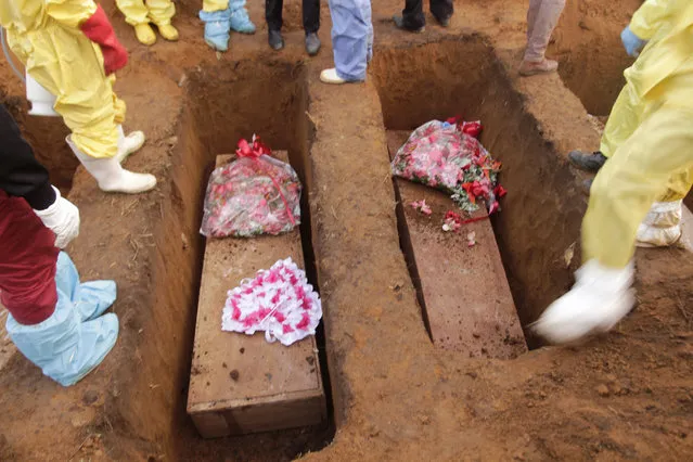 Volunteers bury coffins during a mass funeral for victims of heavy flooding and mudslides in Regent at a cemetery in Freetown, Sierra Leone, Thursday, August 17, 2017. (Photo by Manika Kamara/AP Photo)