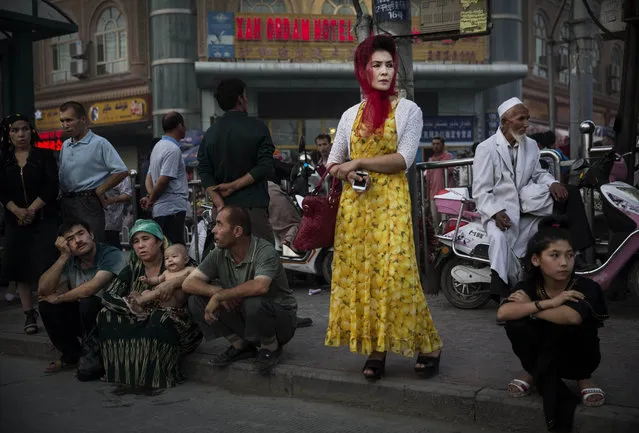 Uyghurs wait at a bus stop on July 27, 2014 in old Kashgar, Xinjiang Province, China. (Photo by Kevin Frayer/Getty Images)