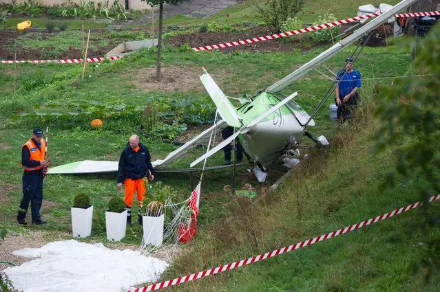 Swiss police officers inspect the wreckage of a plane involved in a collision with a second plane during an airshow on August 23, 2015 in Dittingen, near Basel, northern Switzerland. According to a Swiss news agency, a pilot died and the second pilot – both from the Wurttemberg state in Germany – managed to eject and parachute himself to land safely. (Photo by Sebastien Bozon/AFP Photo)