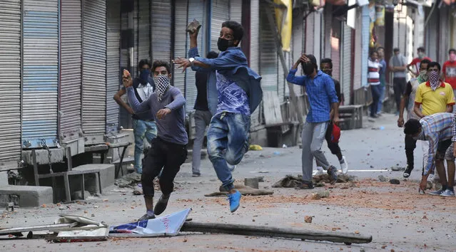 Kashmiri Muslim protesters throw stones at Indian policemen during clashes in Srinagar, the summer capital of Indian Kashmir, 11 July 2016. Clashes between civilians and police in India's northern region of Kashmir has spiked to at least 16 in the third day of violent unrest that has engulfed the Valley since the funeral of famed separatist militant Burhan Muzaffar Wani on 09 July. A curfew remains in place in many parts of the city, forbidding people from leaving their houses at any point during the day. (Photo by Farooq Khan/EPA)