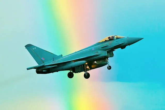 An RAF Typhoon Jet flies through a rainbow at RAF Coningsby in Lincs, United Kingdom on April 6, 2022. The 12 Squadron plane was taking part in a “touch and go” training exercise when it crossed the stream of coloured light. (Photo by John Mountney/Animal News Agency)