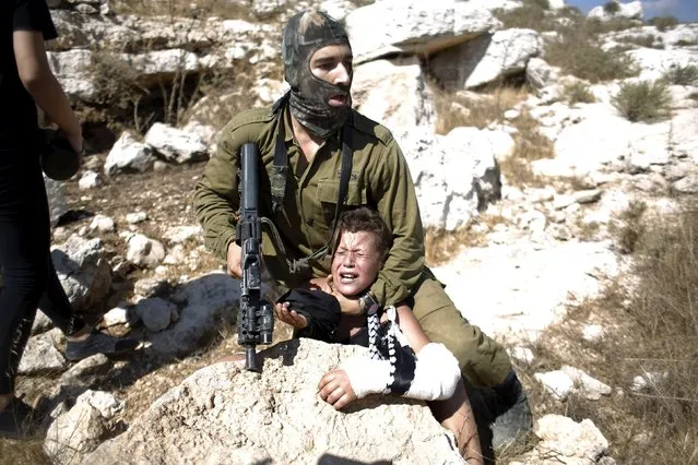 An Israeli soldier detains a Palestinian boy during a protest against Jewish settlements in the West Bank village of Nabi Saleh, near Ramallah August 28, 2015. (Photo by Mohamad Torokman/Reuters)