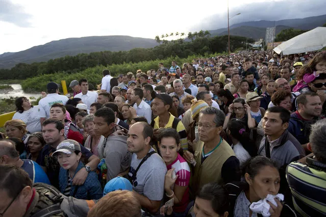 Venezuelans cross the Simon Bolivar bridge linking San Antonio del Tachira, Venezuela, with Cucuta, Colombia, to buy supplies, Sunday, July 17, 2016. Tens of thousands of Venezuelans crossed the border into Colombia on Sunday to hunt for food and medicine that are in short supply at home. It's the second weekend in a row that Venezuela’s government has opened the long-closed border connecting Venezuela to Colombia, and by 6 a.m., a line of would-be shoppers snaked through the entire town of San Antonio del Tachira. (Photo by Ariana Cubillos/AP Photo)