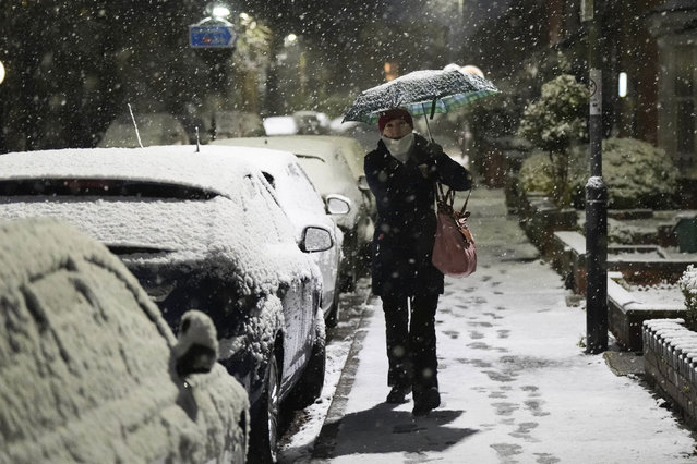 A person walks down a street during snowfall in Warwick, England, Tuesday, November 19, 2024. (Photo by Peter Byrne/PA Wire via AP Photo)