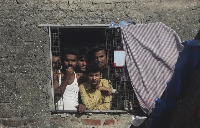 Migrant workers from other states look through the window of a room in Dharavi, one of Asia's largest slums, during lockdown to prevent the spread of the new coronavirus in Mumbai, India, Thursday, April 9, 2020. (Photo by Rafiq Maqbool/AP Photo)