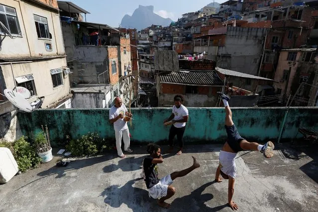 Manoel Pereira Costa (L), known as “Master Manel”, plays the berimbau next to his three sons in the Rocinha favela, in Rio de Janeiro, Brazil, July 25, 2016. (Photo by Bruno Kelly/Reuters)