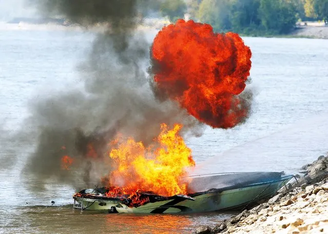 A fireball erupts shortly after QEM firefighters, from Grafton, Ill., reached the shore with a burning boat, on August 31, 2014. The pleasure craft was on fire in the Mississippi River half a mile east of Grafton. QEM fire fire officials said the occupants of the boat safely transferred to a pontoon boat nearby when the fire started. (Photo by John Badman/The Telegraph)