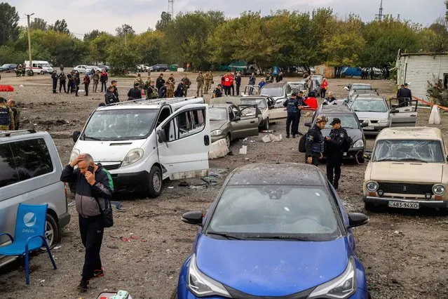 People walk between cars damaged by a missile strike on a road near Zaporizhzhia on September 30, 2022, amid the Russian invasion of Ukraine. Ukraine on September 30, blamed Moscow for shelling a convoy of civilian cars in the southern Zaporizhzhia region that killed at least 23 near the front line. Zaporizhzhia regional governor Oleksandr Starukh said the strikes had also injured 28 people, “all civilians, local people”. (Photo by Kateryna Klochko/AFP Photo)