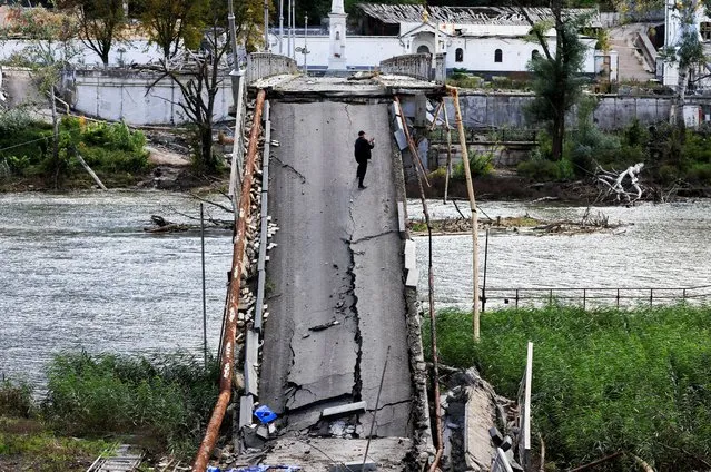 A Man uses his mobile phone as he stands on a bridge destroyed by a Russian Missile strike, amid Russia's attack on Ukraine, in Svyatohirsk, in Donetsk region, Ukraine on October 3, 2022. (Photo by Zohra Bensemra/Reuters)