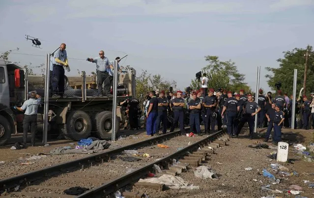 Hungarian police officers stand along the fence at the Serbian border while sealing it near the village of Horgos, Serbia, September 14, 2015, near the Hungarian migrant collection point in Roszke. (Photo by Marko Djurica/Reuters)