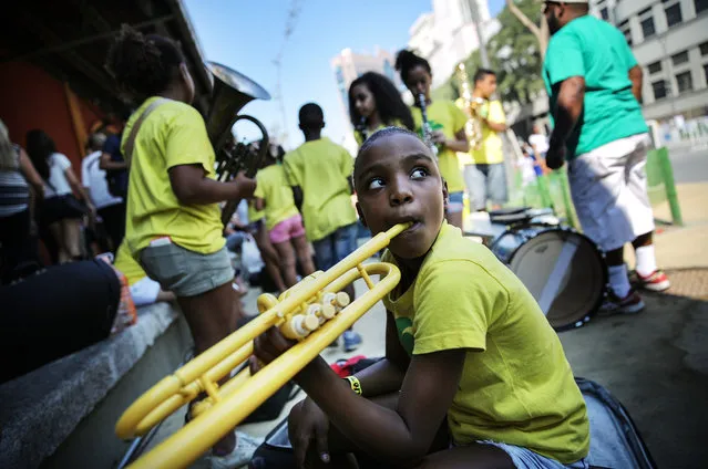  Kids from the band Favela Brass, who hail from the Pereira da Silva “favela” community, wait to perform for Olympic tourists and others along Olympic Boulevard on August 17, 2016 in Rio de Janeiro, Brazil. Around 40 students are part of the project which provides free music and English lessons to children from the “favela” community. The band is playing on the Olympic Boulevard with donated instruments most days during the Olympics. (Photo by Mario Tama/Getty Images)