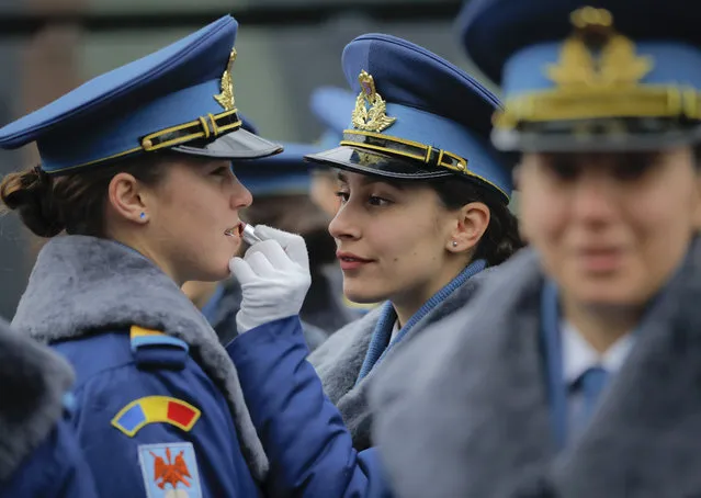 A female member of Romania's military applies lipstick on a colleague's lips before Romania's national day military parade in Bucharest, Romania, Friday, December 1, 2017. Thousands of Romanian troops staged a military parade to celebrate Romania's national day, but key politicians didn't attend, signaling tensions between the president and the ruling left-wing coalition over plans to revamp the justice system. (Photo by Vadim Ghirda/AP Photo)