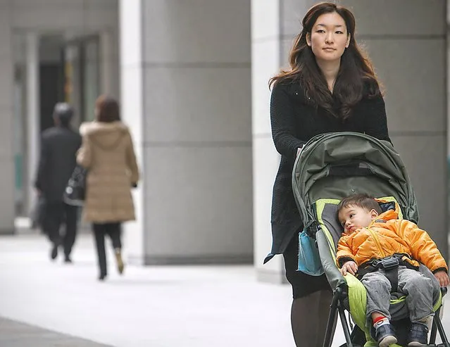 Yoko Furukawa, an employee at Nippon Yusen K.K., pushes a baby stroller during the morning commute in the Marunouchi district of Tokyo, Japan, on Monday, December 14, 2009. Japan's efforts to escape a deflationary spiral and sustain an economic recovery may hang on whether Furukawa's son finds a place in day care. Prime Minister Yukio Hatoyama wants to encourage working mothers such as Furukawa as a means to fuel household demand and help fund pensions and health care. The Dai-ichi Life Research Institute says a 0.6 percentage-point rise in Japan's female employment rate would boost consumer spending by 1.3 percent and increase the Nikkei 225 Stock Average by 3.2 percent. (Photo by Tomohiro Ohsumi/Blomberg)