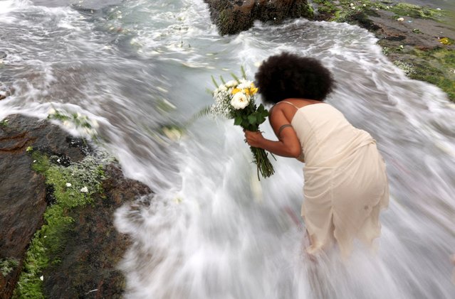 A woman pays tribute to Yemanja, Afro-Brazilian goddess of the sea, on Yemanja Day, in Arpoador Beach in Rio de Janeiro, Brazil, on February 2, 2024. (Photo by Ricardo Moraes/Reuters)