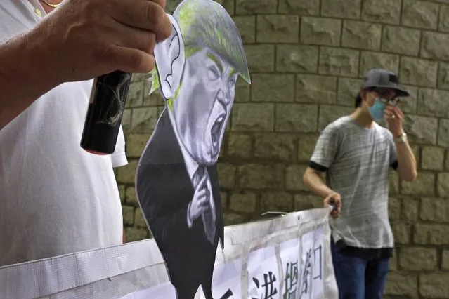 Pro-China supporters displays a picture of U.S. President Donald Trump during a protest against the U.S. sanctions outside the U.S. Consulate in Hong Kong Saturday, August 8, 2020. The U.S. on Friday imposed sanctions on Hong Kong officials, including the pro-China leader of the government, accusing them of cooperating with Beijing's effort to undermine autonomy and crack down on freedom in the former British colony. (Photo by Vincent Yu/AP Photo)