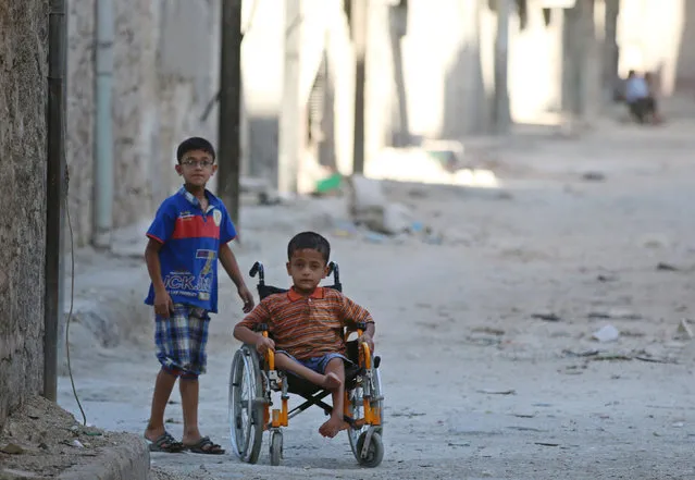 Boys, one of them in a wheelchair, go down a street in the rebel-held al-Sheikh Said neighbourhood of Aleppo, Syria September 1, 2016. (Photo by Abdalrhman Ismail/Reuters)