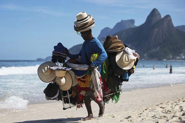 A vendor walks with his hats and beachwear along Ipanema Beach in Rio de Janeiro, Sunday, May 25, 2025. (Photo by Bruna Prado/AP Photo)