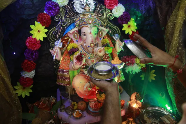 In this Tuesday, September 6, 2016 photo, Raju Laljibhai Dipikar offers kheer, an Indian sweet, to an idol of elephant-headed Hindu god Ganesha at their house on the second day of Ganesha Chaturthi festival in Mumbai, India. (Photo by Rafiq Maqbool/AP Photo)