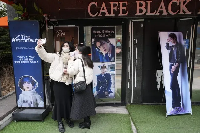 Women take a selfie with images of BTS's member Jin in front of a cafe in Seoul, South Korea, Monday, December 12, 2022. South Korean media report that Jin is going to enlist the military service on Tuesday. (Photo by Ahn Young-joon/AP Photo)