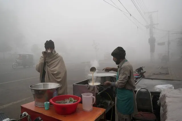 A man drinks tea at a roadside stall as heavy fog reduces visibility in Lahore, Pakistan, Monday, January 2, 2023. (Photo by K.M. Chaudary/AP Photo)