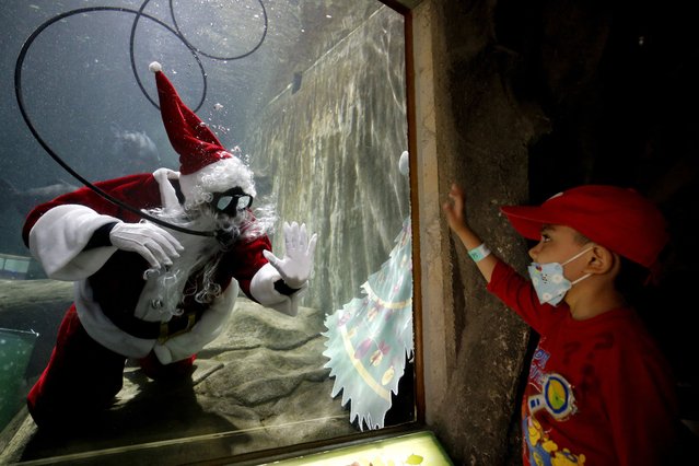 A man dressed as Santa Claus performs for visitors inside a fish tank at the Guadalajara Zoo aquarium days before the Christmas holidays in Guadalajara, Jalisco state, Mexico, on December 16, 2022. (Photo by Ulises Ruiz/AFP Photo)