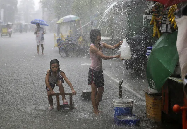 Girls play along a flooded street during heavy rains brought on by tropical storm “Nesat” on the outskirts of Manila, Philippines on Thursday, July 27, 2017. Strong rains caused floods in low-lying areas and classes were suspended in most schools in the capital. (Photo by Aaron Favila/AP Photo)
