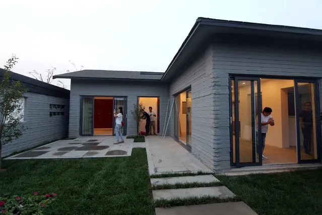 This photo taken on September 24, 2016 shows people visiting a villa built by 3D printing technology at a village in Binzhou, eastern China's Shandong province. The 3D-printed villa which uses no bricks in its construction costs 5,000 yuan (750 USD) per square meter. (Photo by AFP Photo/Stringer)