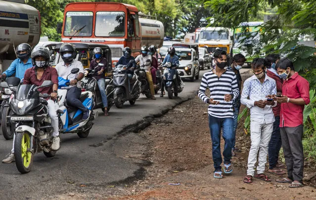 Commuters wearing masks wait at a traffic intersection in Kochi, Kerala state, India, Monday, September 28, 2020. India's confirmed coronavirus tally has crossed 6 million cases, only second behind the United States, as the south Asian country continues to battle the worst COVID-19 outbreak in the world. (Photo by R.S. Iyer/AP Photo)