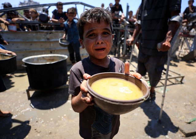 A Palestinian child holds a bowl with food received from a charity kitchen, amid a hunger crisis, in Gaza City on July 24, 2025. (Photo by Dawoud Abu Alkas/Reuters)