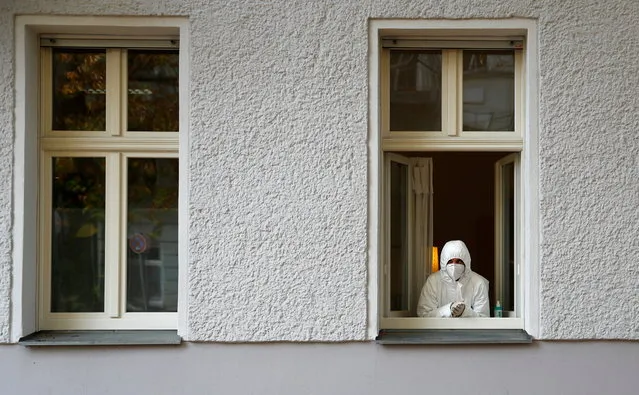 A medical staff member looks out of a window of a general practitioner's office which offers the coronavirus tests, as the COVID-19 spread continues in the Mitte district of Berlin, Germany, October 28, 2020. (Photo by Fabrizio Bensch/Reuters)