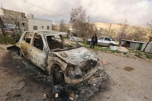 A Palestinian man checks a charred car after it was allegedly set on fire by Israeli settlers in the village of Jalud, south of Nablus, in the occupied West Bank on January 30, 2023. (Photo by Jaafar Ashtiyeh/AFP Photo)