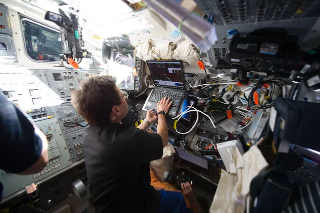 NASA astronaut Greg Chamitoff uses a laptop on the aft flight deck of space shuttle Endeavour during rendezvous and docking operations with the International Space Station on May 18, 2011. (Photo by Reuters/NASA)