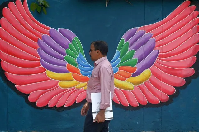 A man walks past a wall mural along a street corner in Mumbai on March 10, 2023. (Photo by Indranil Mukherjee/AFP Photo)