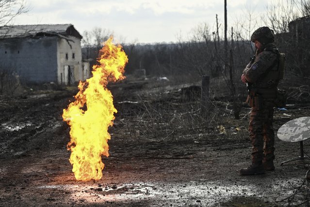 A Ukrainian serviceman stands near a fire lit with gun powder to get warm near the city of Bakhmut in the region of Donbas on March 5, 2023, amid the Russian invasion of Ukraine. (Photo by Aris Messinis/AFP Photo)