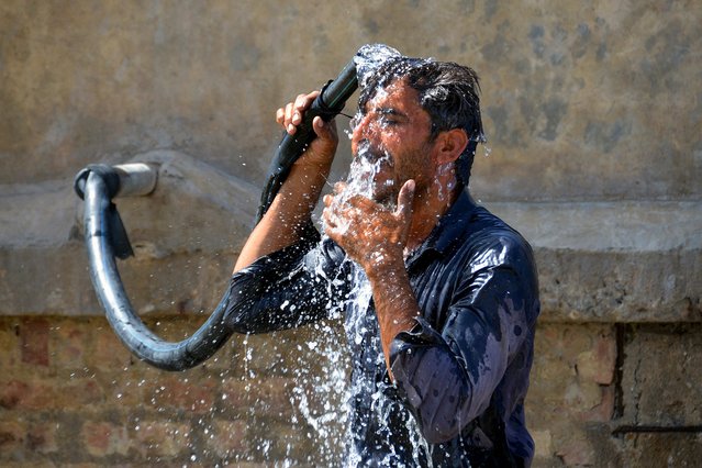 A man bathes with water from a pipe on a hot summer day in Jaffarabad, in Pakistan's Balochistan province on May 30, 2024, amid the ongoing heatwave. Pakistan's meteorological office has forecast three heatwaves – one already underway and two more set to hit in early and late June. (Photo by Fida Hussain/AFP Photo)