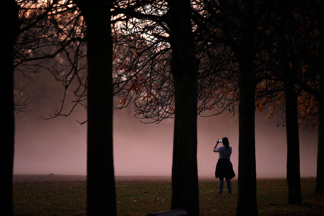 A person takes a photograph of morning mist at sunrise in Greenwich Park in south London on November 9, 2020. (Photo by Daniel Leal-Olivas/AFP Photo)