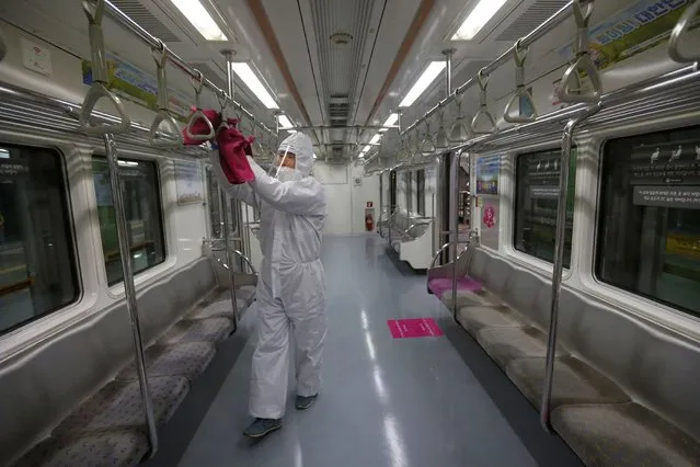 An employee disinfects handles as a precaution against the coronavirus on a subway train at a subway station in Seoul, South Korea, Thursday, December 10, 2020. South Korea has reported another new 682 cases of the coronavirus, as officials work to expand testing to slow transmissions. (Photo by Ahn Young-joon/AP Photo)
